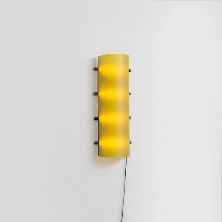 De Connection Clamp Lamp in Lemon yellow kan je neerzetten maar ook aan de wand hangen. Je krijgt hiervoor een speciale beugel geleverd.
