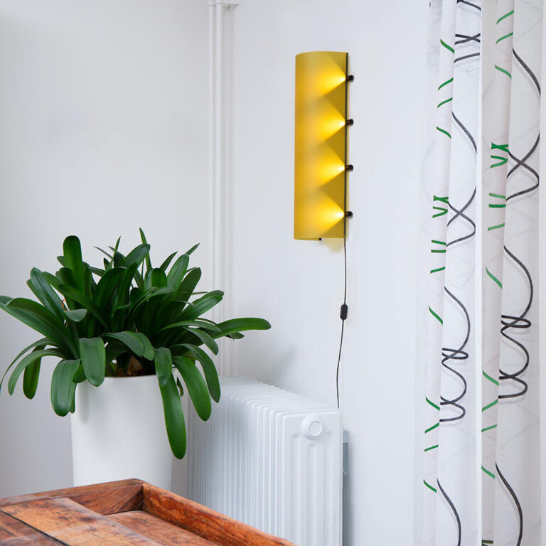 De Connection Clamp Lamp in Lemon yellow hangt hier in een witte hoek van de kamer. Het geeft het hoekje een zonnige look.