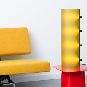 De Connection Clamp Lamp in Lemon yellow als schemerlamp op een moderne rode tafel en naast een strak gele bank.