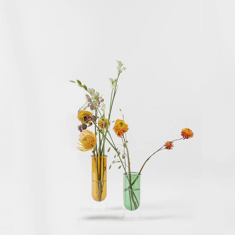 De Flower Tube design vaas bestaat uit twee delen: een gekleurde glazen vaas, die rust in een doorzichtige cilinder van glas.
