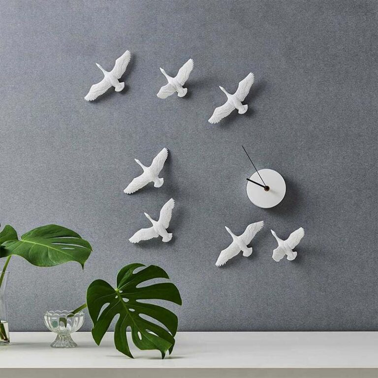De witte ganzen van de Migrantbird klok die in V-formatie vliegen, steken prachtig af op de grijze muur.