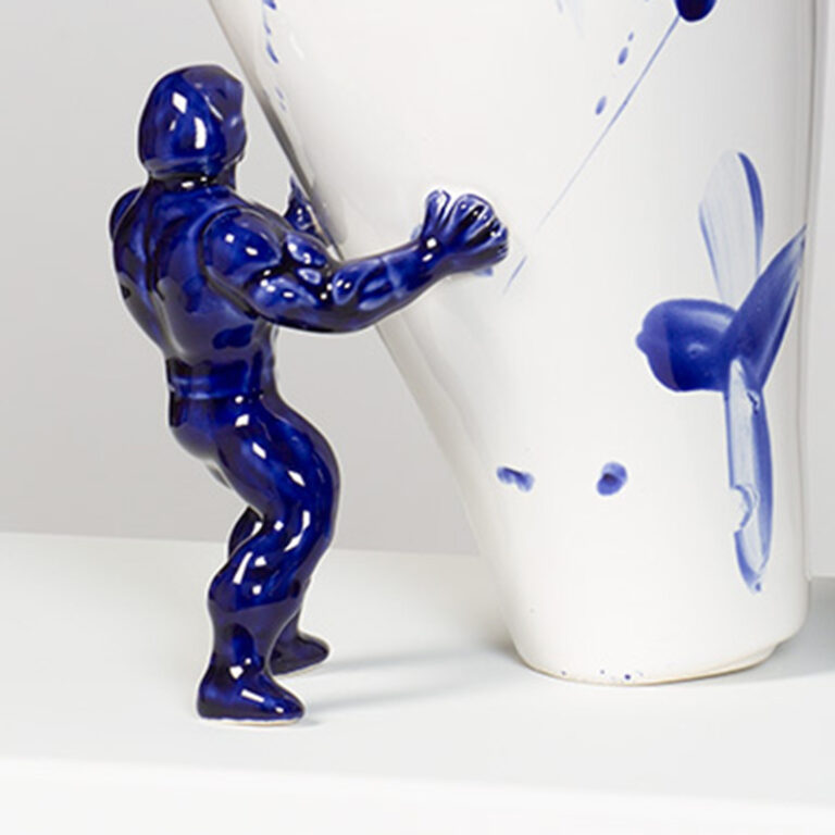 Een detail van de Delfts blauwe vaas van Jasmin Djerzic. Je ziet dat de blauwe Super hero de vaas tegenhoudt.