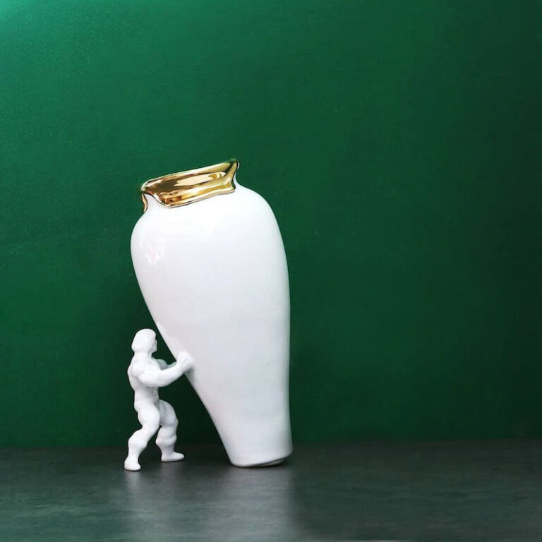 My Superhero vaas in wit met een gouden rand steekt mooi af tegen een groene muur. Design Jasmin Djerzic.