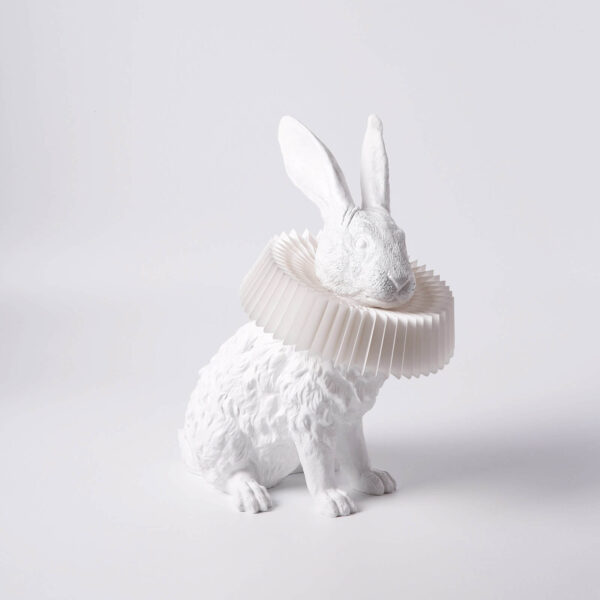 De Rabbit X lamp zitten vanaf de zijkant gezien. Het konijn en zijn kraag zijn beiden wit.