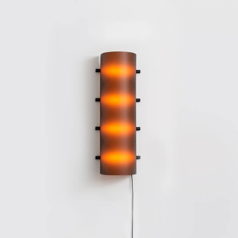 De Connection Clamp Lamp in Chocolate brown aan de wand. Je ziet de 4 brandende Led lampen die een mooie sfeer geven.