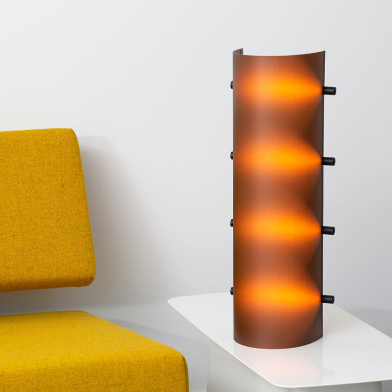 De Connection Clamp Lamp in Chocolate brown als schemerlamp op een bijzet tafel. Een design object om van te genieten.