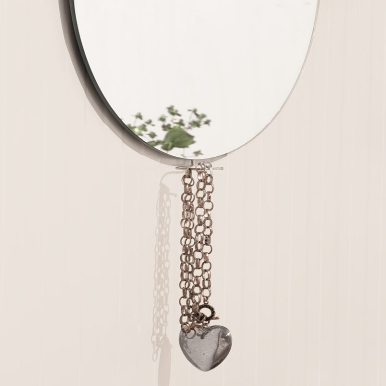 Design Spiegel Mirror hanger heeft aan de boven en de onderzijde een houten kleerhanger aan de achterzijde. Aan de onderste kun je bijvoorbeeld je sieraden aan ophangen.