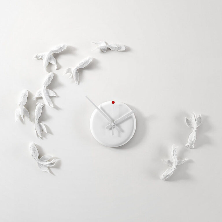In plaats van een wijzerplaat zwemmen 9 witte goudvissen rond het uurwerk van de witte Goldfish design klok van Hao Shi.