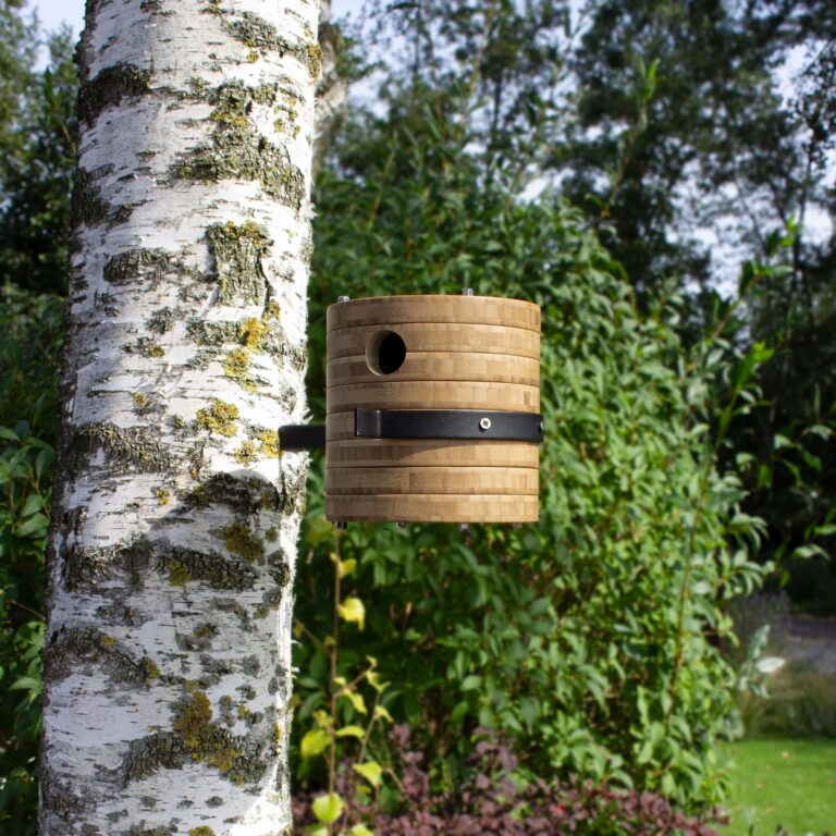 Hangend aan een boom is het bamboe vogelhuis Fly-inn wandmodel een opvallende verschijning.