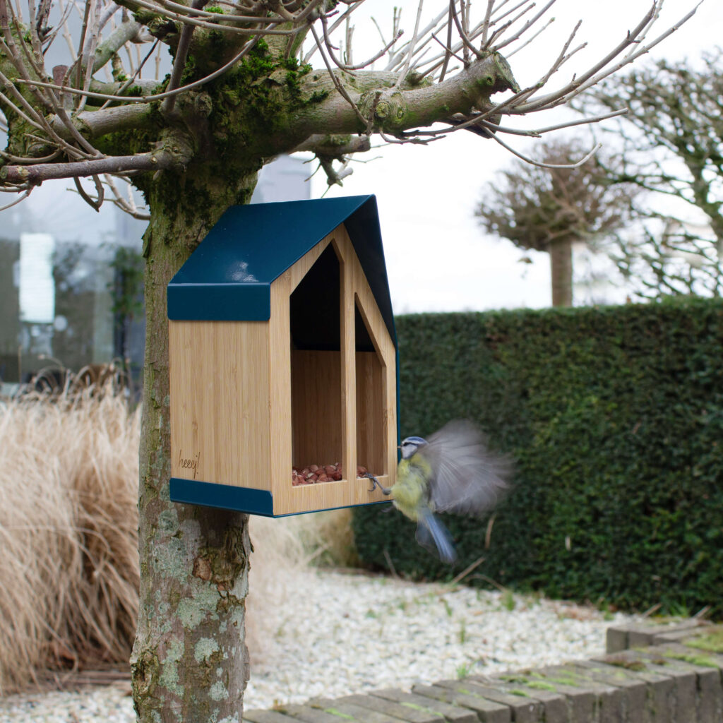 De vormgeving van het Happy Bird Feeder Vogelvoederhuisje is gebaseerd op moderne architectuur. Een koolmees komt net aanvliegen.