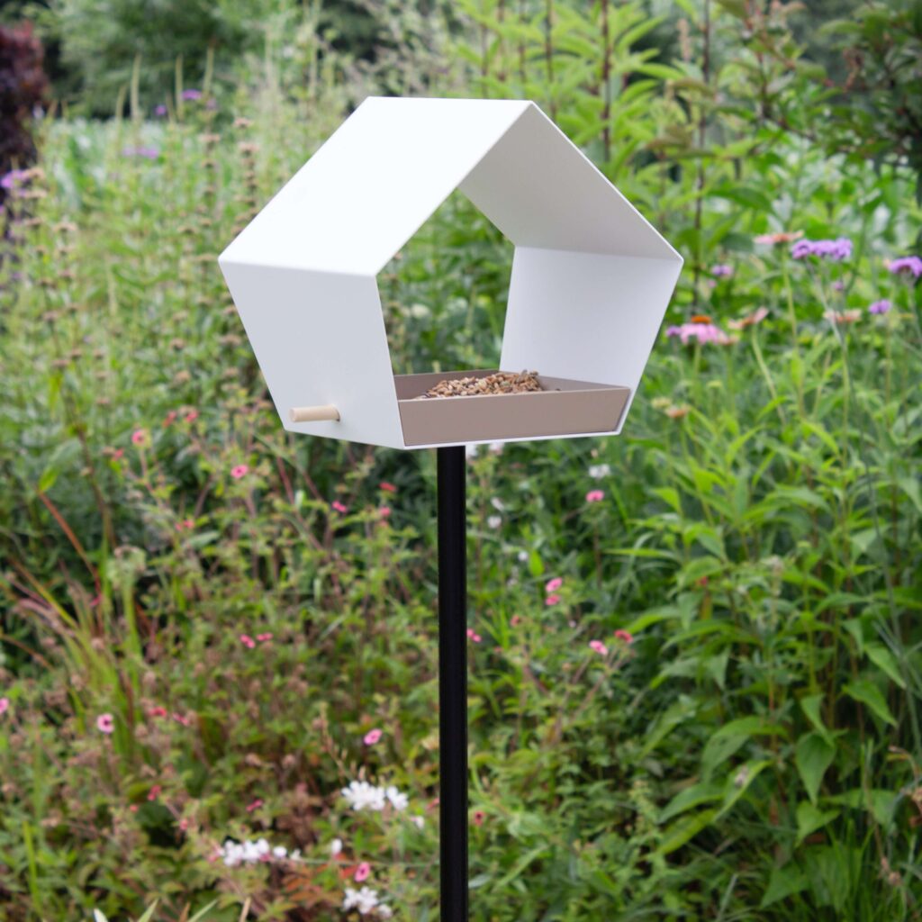 Vogelvoederhuisje Big Diamond met helder wit huisje en natuurlijke kleuren in een weelderige tuinsetting