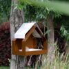 Modern vogelvoederhuis voor aan de wand, gezien van de zijkant met een vetebol in de schaal